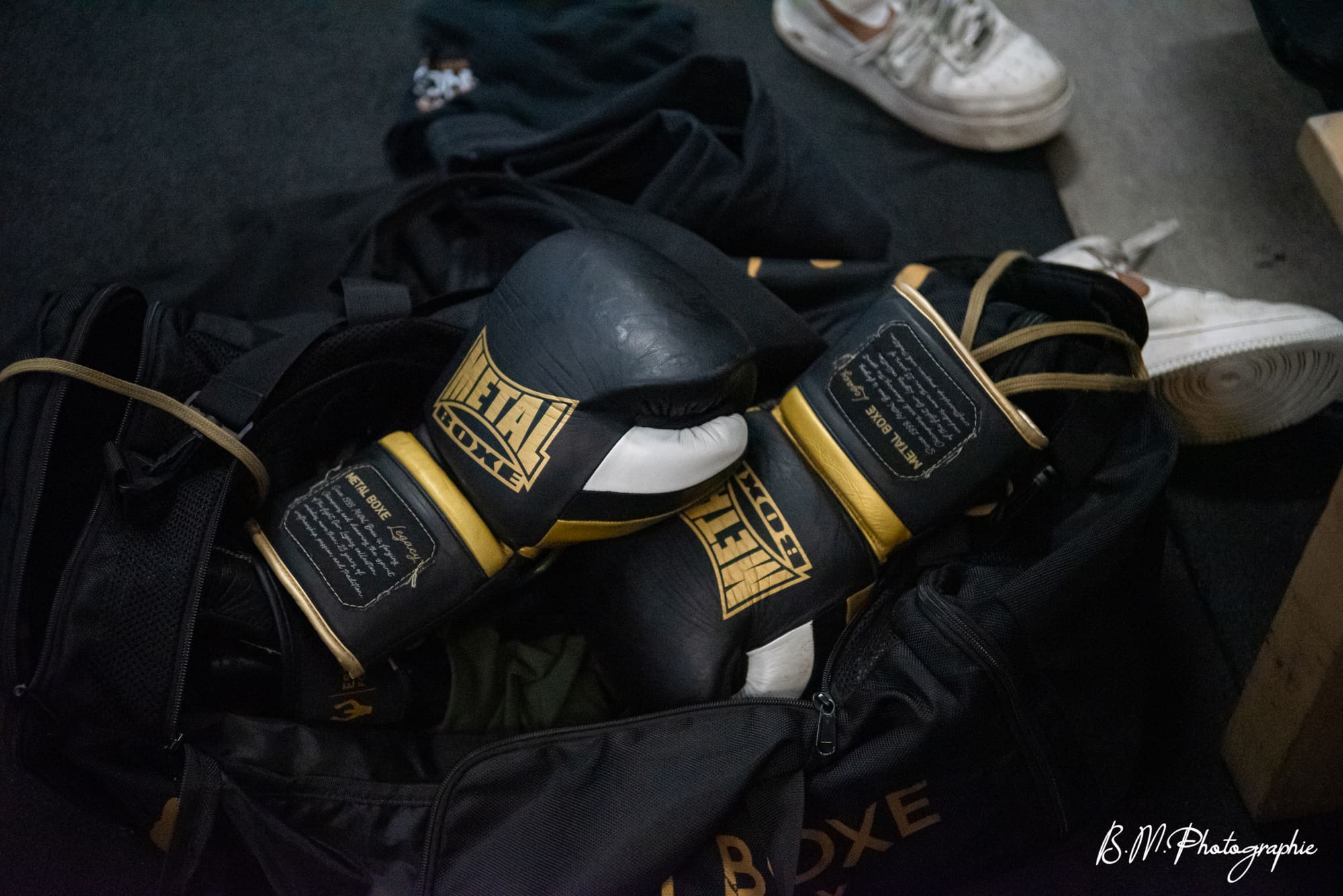 Gants de boxe et casque de protection posés sur un sac de sport dans le vestiaire.