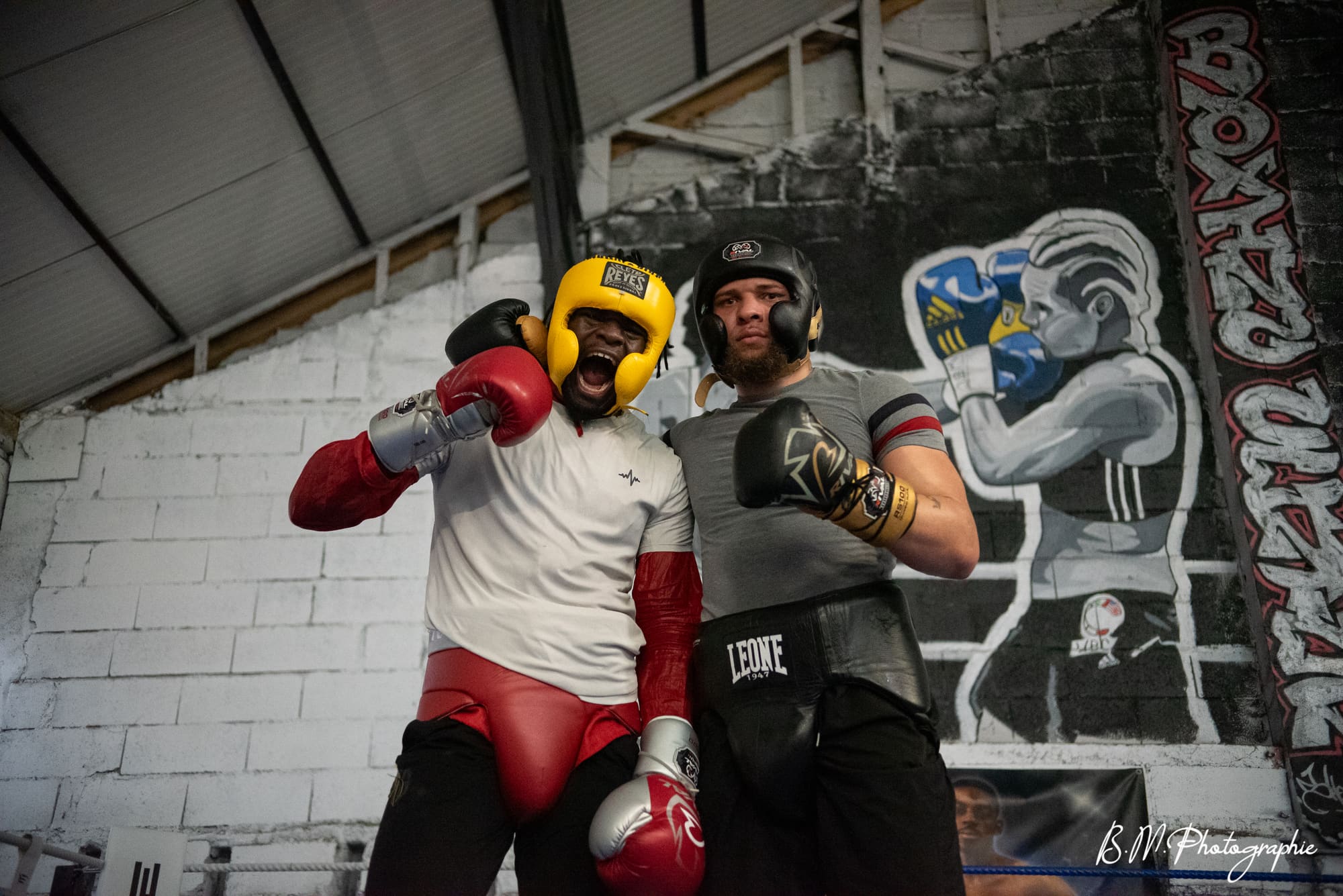 Deux boxeurs casqués en opposition contrôlée pendant une séance de sparring.